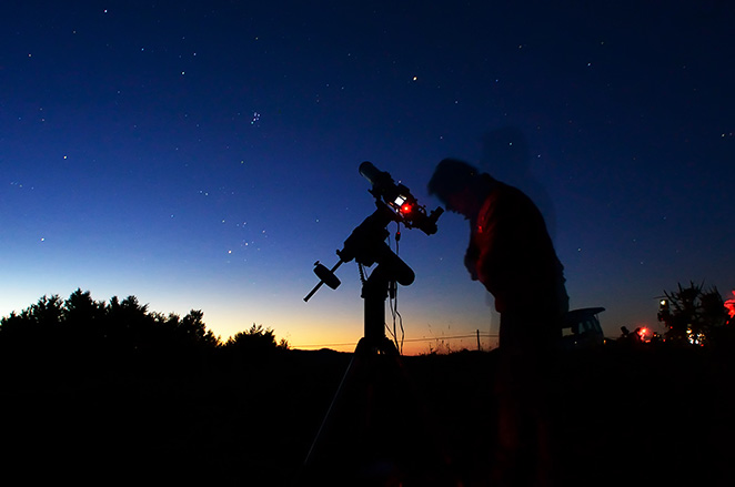 Человек смотрит в телескоп на небо